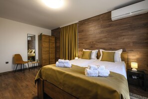 A hotel room with a wooden headboard, a bed with white linens, a desk with a chair, and a mirror.
