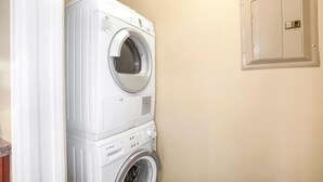 Eine nebeneinander gestellte Waschmaschine und ein Trockner in einem Waschraum mit einer beigen Wand und einem Hauswirtschaftsschrank.