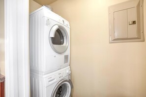 A stacked washer and dryer unit in a laundry room with a beige wall and a utility panel. - Honua Kai Close To Beach 3 Free Rental Cars KBM Resorts 3 Units, 6 Bedrooms HK Ml-2666 (Kaanapali)