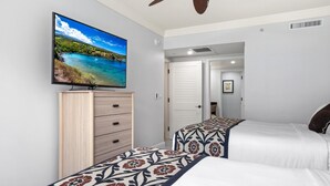 Ein Schlafzimmer mit zwei Betten, einem Fernseher auf einem Schrank und einem Deckenventilator.