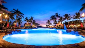 A large, illuminated swimming pool surrounded by palm trees and lounge chairs, with buildings in the background. - Honua Kai Close To Beach 2 Free Rental Cars KBM Resorts 2 Units, 5 Bedrooms HK Ml-2651 (Kaanapali)