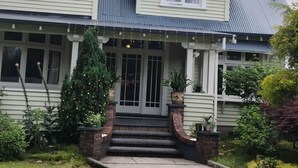 A two-story house with a front porch, a Christmas tree, and a brick staircase leading to the entrance. - LLU HOMES FOR EXPLORERS (Westport)