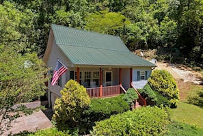 A house with a green roof, a porch, and an American flag.