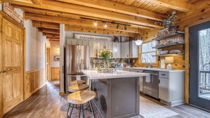 A kitchen with a central island, wooden cabinetry, a refrigerator, and a sign reading 'Farmers Market.' - Timber Breeze - game room, hot tub, pets, firepit (Blue Ridge)