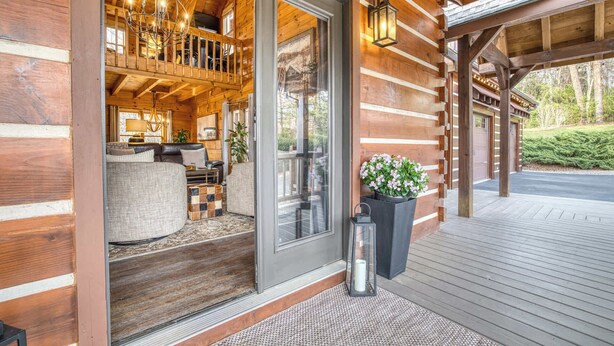 A log cabin with a cozy interior, a porch with a bench, and a garage. - Timber Breeze - game room, hot tub, pets, firepit (Blue Ridge)