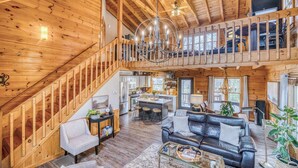 A spacious loft-style living area with a staircase, a dining area, and a kitchen. - Timber Breeze - game room, hot tub, pets, firepit (Blue Ridge)