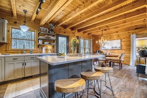 Ein Holzblockhaus-Innenraum mit Küche, Essbereich und Bar.