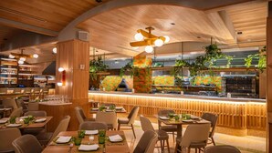 A restaurant with wooden ceiling, bar area, and dining tables with chairs.