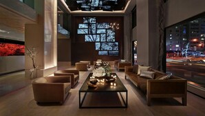 A modern lounge with sofas, a coffee table, and a large window with city lights visible outside.
