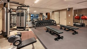 Ein Fitnessstudio mit Krafttrainingsgeräten, Kurzhanteln, Bänken und Trainingsbällen.