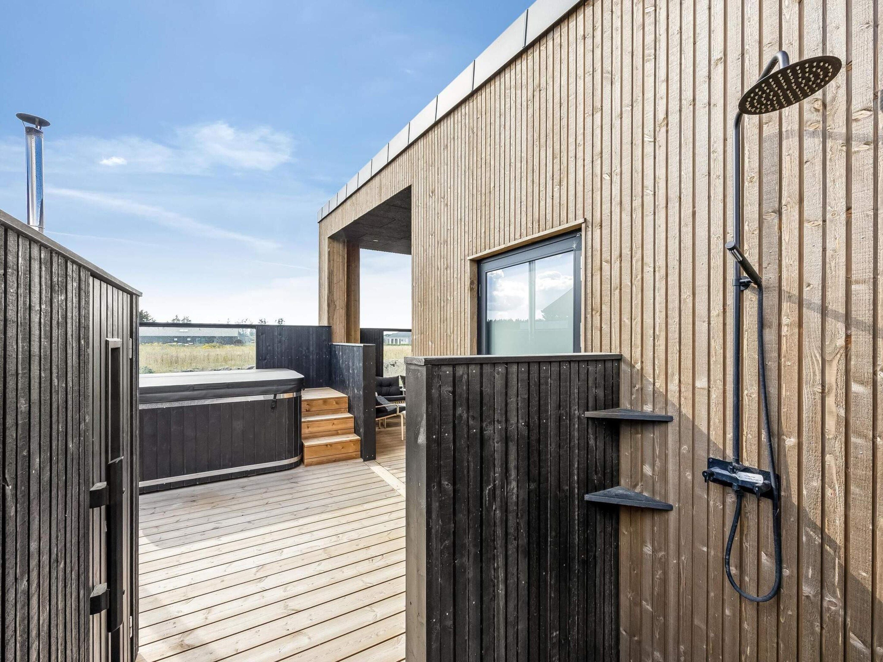A wooden deck with a hot tub and a shower.