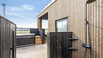 A wooden deck with a hot tub and a shower.