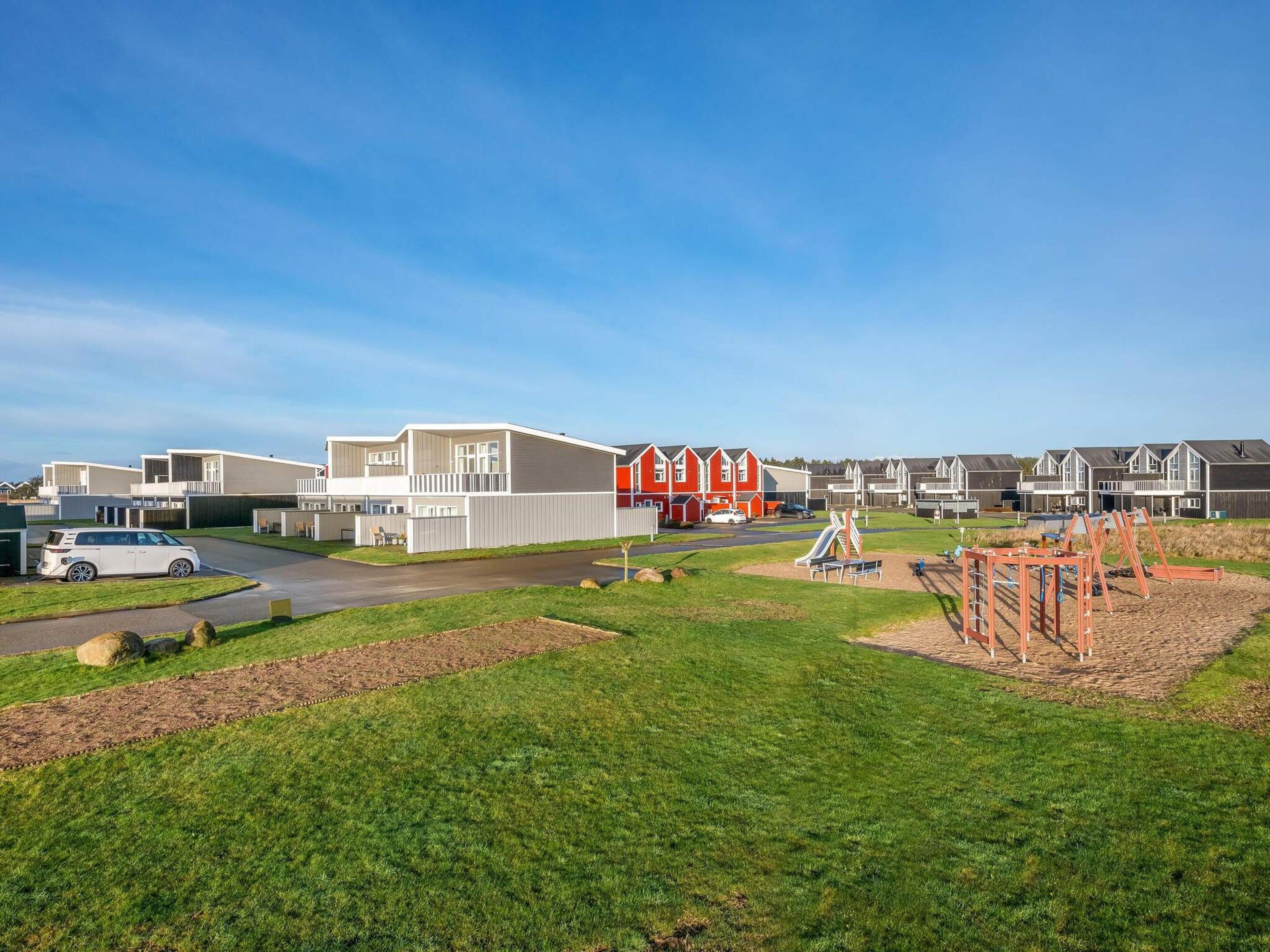 A residential area with modern houses, a playground, and a parking area.