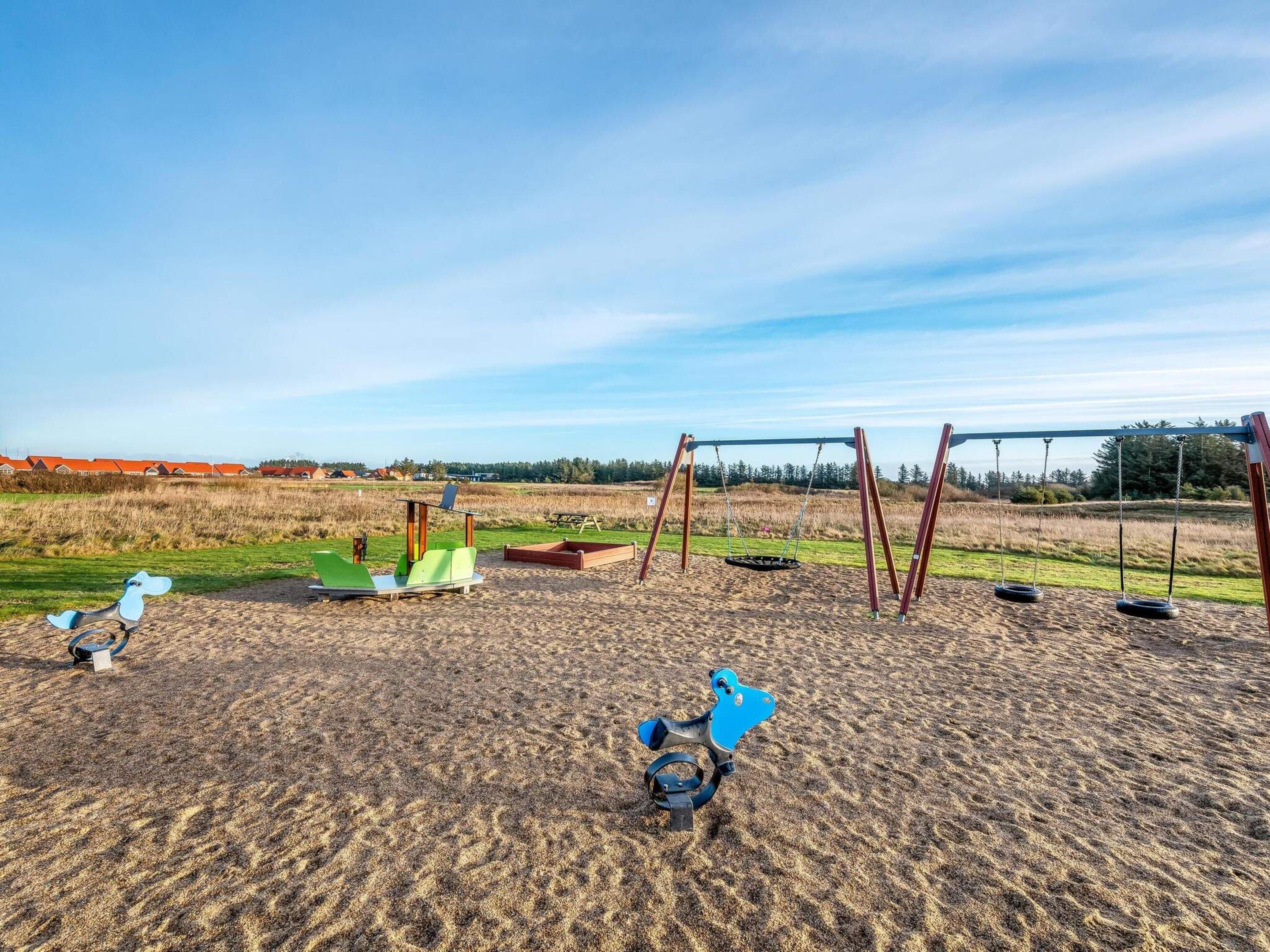 A playground with swings and a slide in a grassy field.