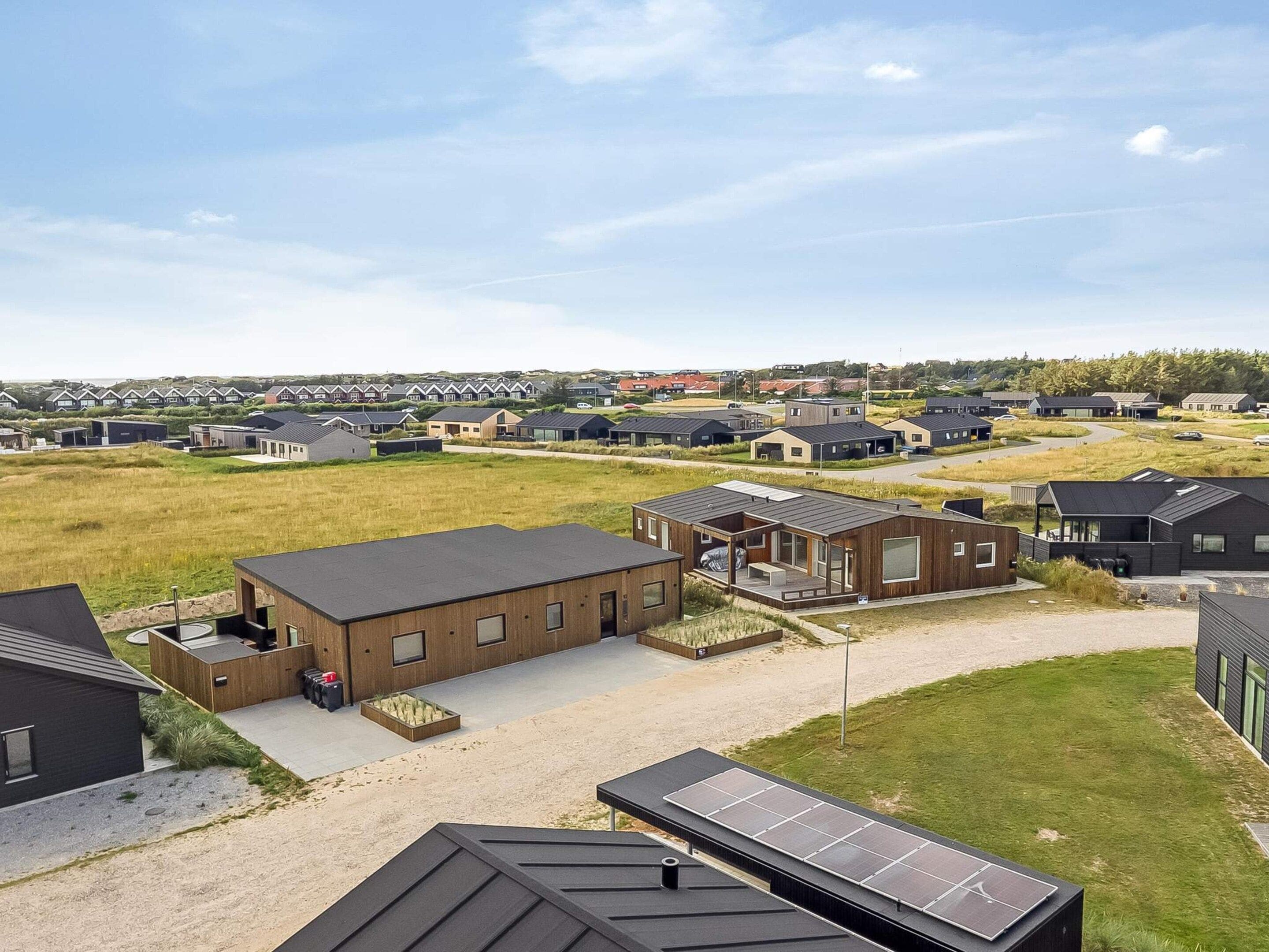 Un quartier résidentiel avec des maisons modernes, une allée pavée et des panneaux solaires installés sur un bâtiment.
