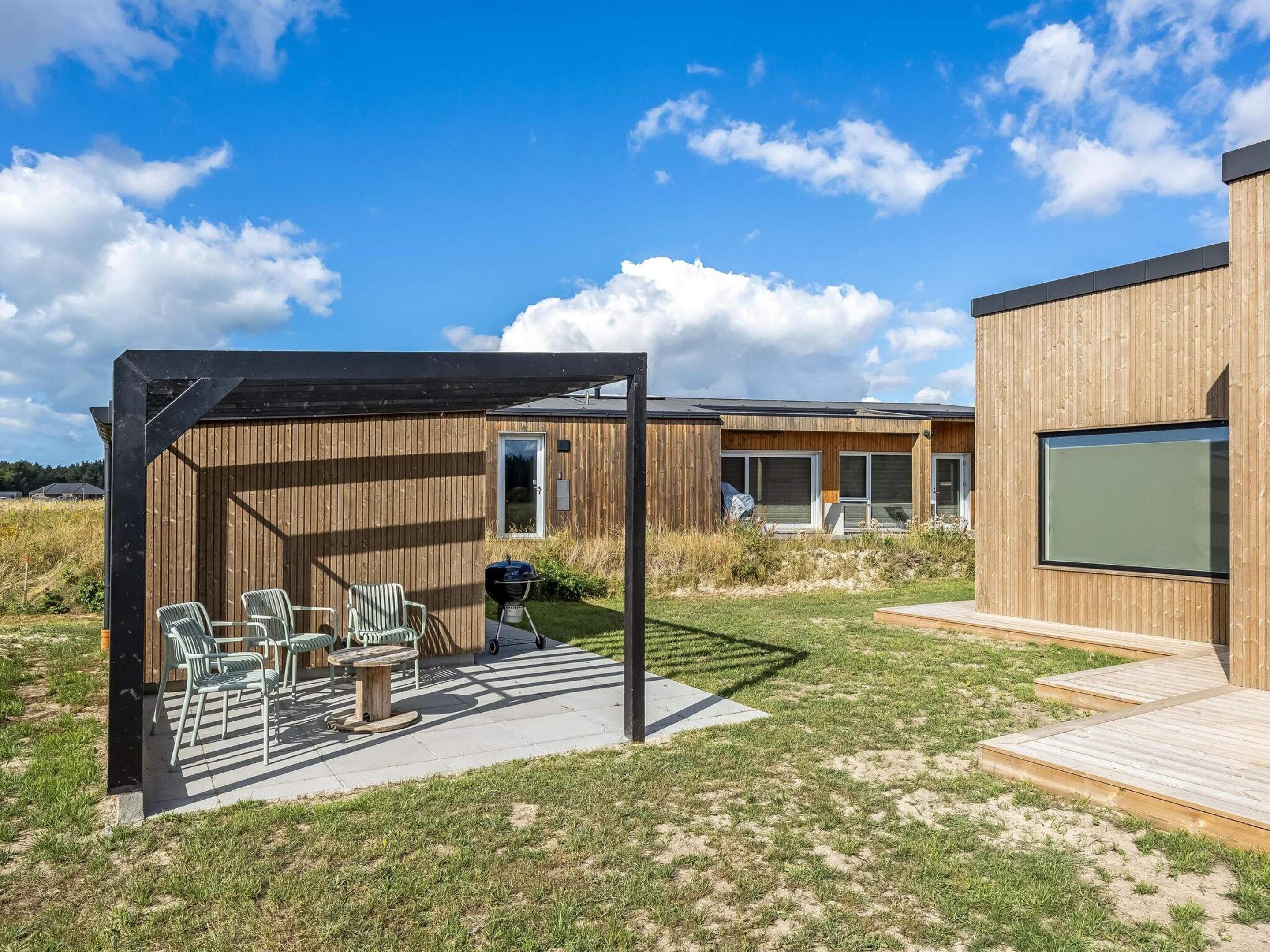 Eine moderne Terrassenanlage im Freien mit Sitzgelegenheiten und einem Grill.