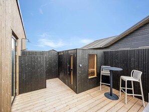 A wooden deck with a table and chairs, a door, and a window. - 4 Star Holiday Home in Lokken (Lokken)