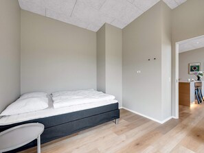 A bedroom with a bed, a chair, and a kitchenette area. - 4 Star Holiday Home in Lokken (Lokken)