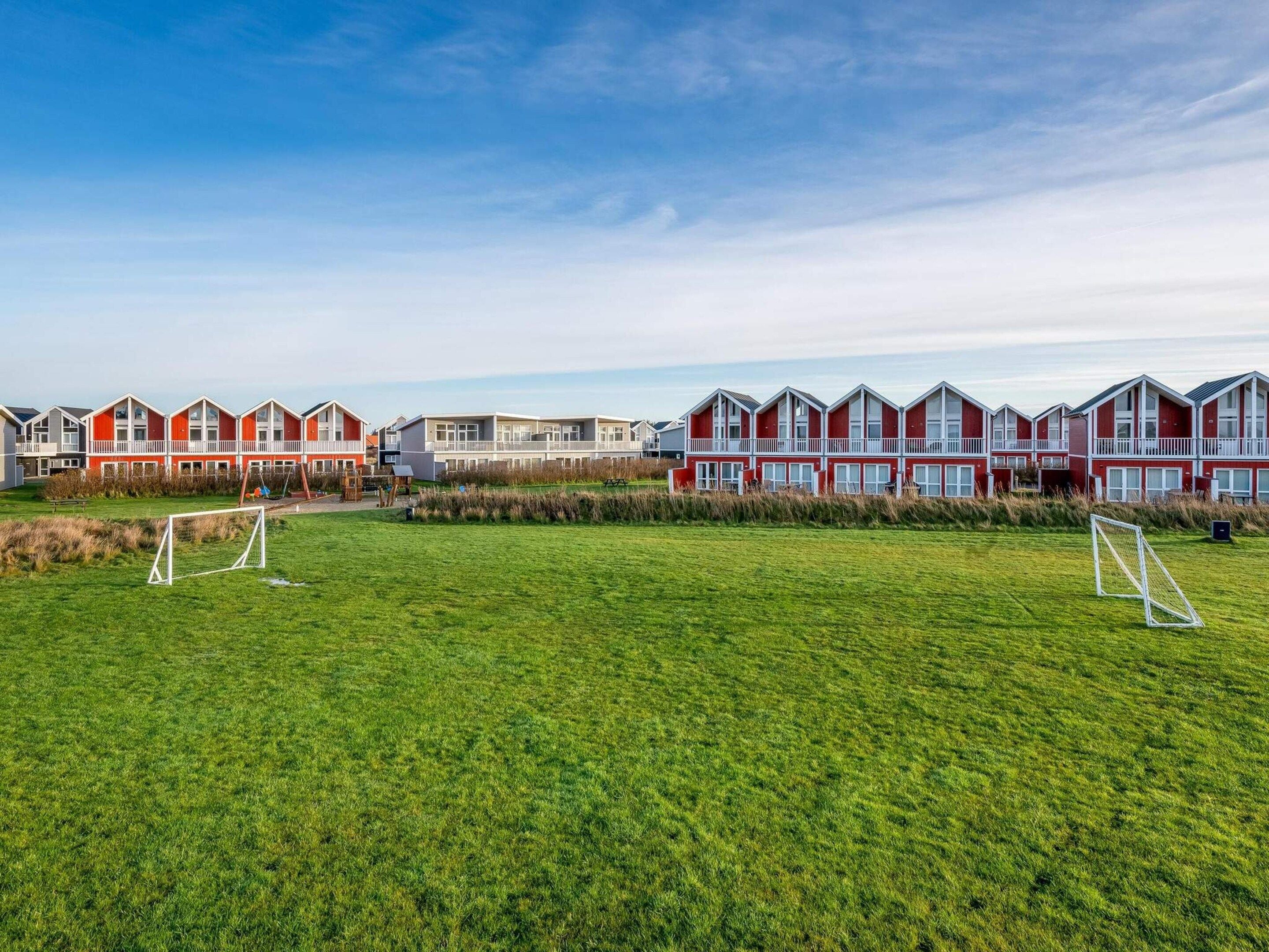 A row of red and white houses with a grassy field in the foreground.