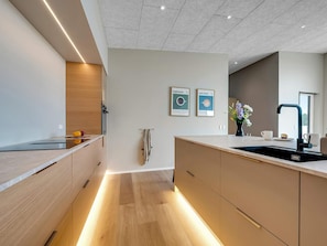 A modern kitchen with a central island, built-in appliances, and pendant lighting. - 4 Star Holiday Home in Lokken (Lokken)