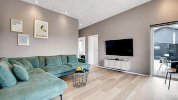 A modern living room with a sectional sofa, a flat-screen TV, and a herringbone-patterned floor.
