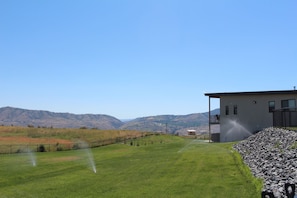 Un campo cubierto de hierba con un edificio, una cerca y montañas al fondo.