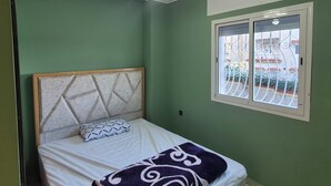 Een kamer met een bed, een raam met uitzicht op een balkon en een plafondlamp.