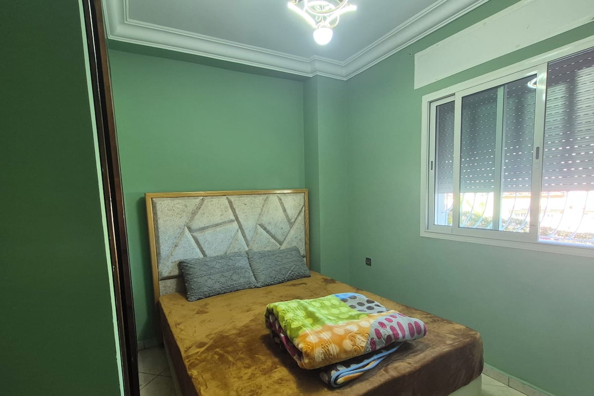 Un dormitorio con una cama, una ventana y una lámpara en el techo.