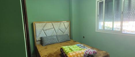 Un dormitorio con una cama, una ventana y una lámpara en el techo.