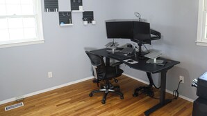 A room with a wooden floor, a desk with a computer, a chair, a ceiling fan, and a window. - Wonderful 2-bedroom house in charming Augusta (Augusta)