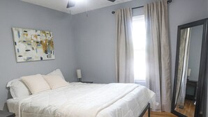 A bedroom with a bed, ceiling fan, wooden floor, and a large mirror. - Wonderful 2-bedroom house in charming Augusta (Augusta)