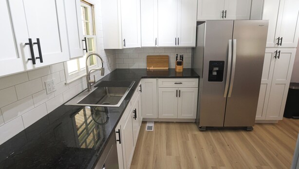 A kitchen with white cabinets, a stainless steel refrigerator, a black countertop, and a wooden cutting board. - Wonderful 2-bedroom house in charming Augusta (Augusta)