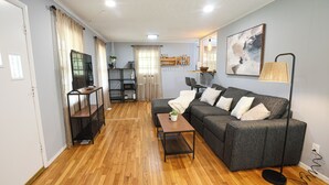 A living room with a sofa, coffee table, TV, and a dining area with chairs and a table. - Wonderful 2-bedroom house in charming Augusta (Augusta)
