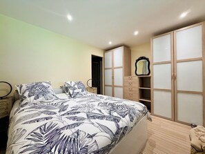 Ein Schlafzimmer mit einem Bett, einem Nachttisch, einem Spiegel und einem Kleiderschrank mit Schiebetüren.