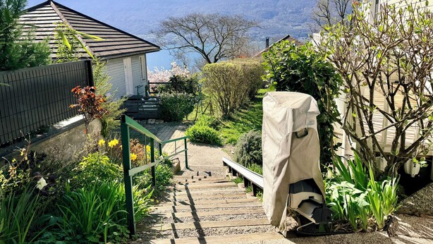 A garden with a wooden staircase leading to a house, surrounded by greenery and a view of mountains. - Grand T3 en Rez-de-jardin Tresserve (Tresserve)