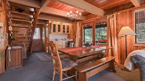 A wooden interior with a dining table, chairs, a chandelier, and a kitchen area. - Rivers Edge, 3 bedroom cabin with River Access (Garden Valley)