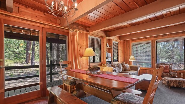 A cozy cabin interior with a wooden dining table, benches, a sofa, and a chandelier. - Rivers Edge, 3 bedroom cabin with River Access (Garden Valley)