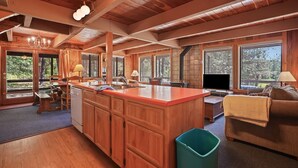 A spacious kitchen with wooden cabinets, a large island, and a dining area with a table and chairs. - Rivers Edge, 3 bedroom cabin with River Access (Garden Valley)