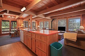 A spacious kitchen with wooden cabinets, a large island, and a dining area with a table and chairs. - Rivers Edge, 3 bedroom cabin with River Access (Garden Valley)