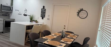 Una cocina moderna con comedor, un reloj y un cartel de bienvenida.