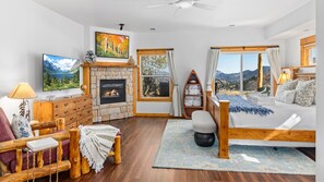 A cozy room with a fireplace, a bed, a sofa, and a television. - Mountain View Condo w/Hot Tub (Estes Park)