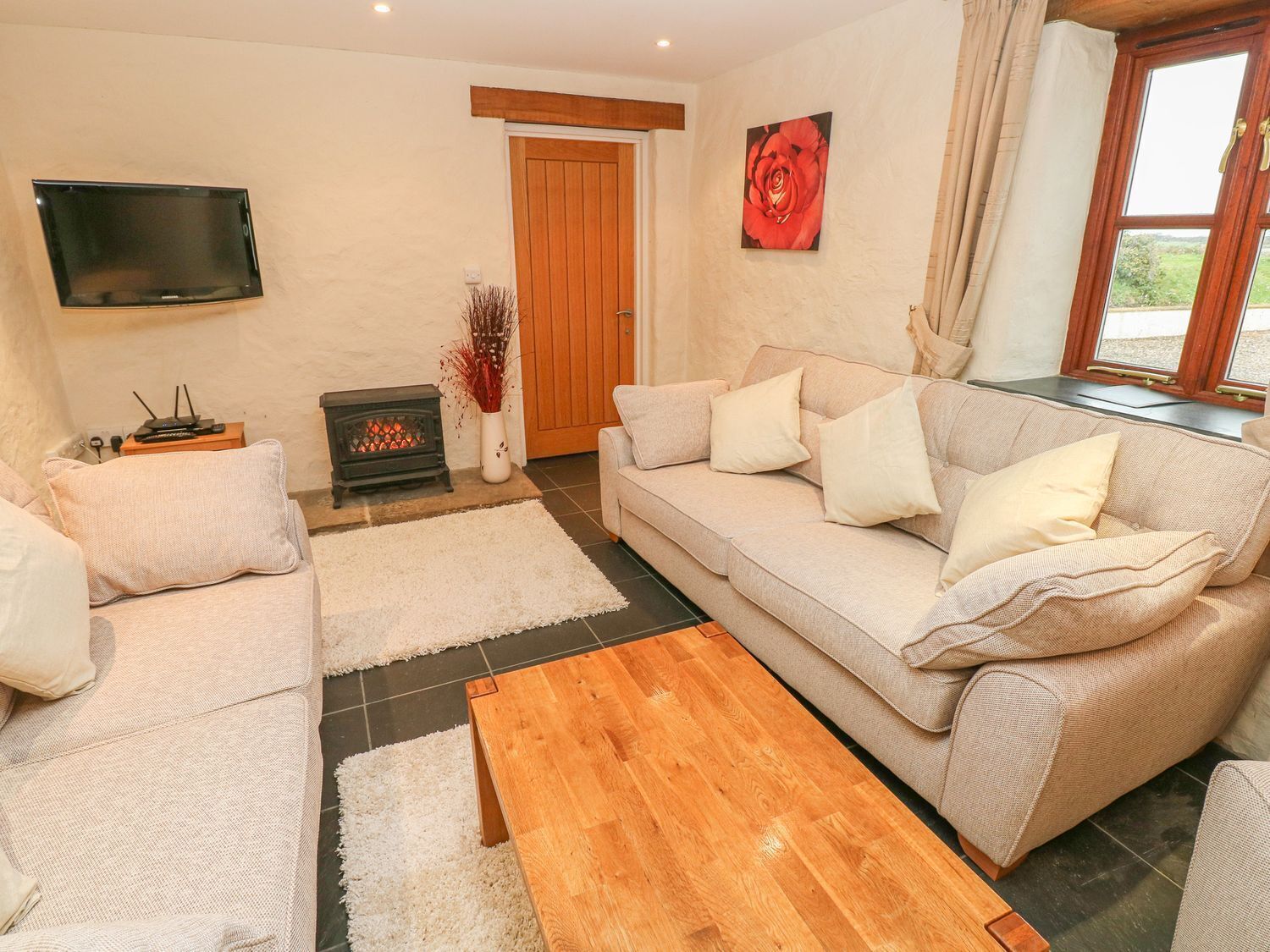 A living room with a sofa, a coffee table, a fireplace, a television, and a window with curtains.