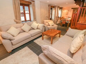 Un saló amb sofà, butaques, taula de centre i zona de menjador amb cadires i taula.