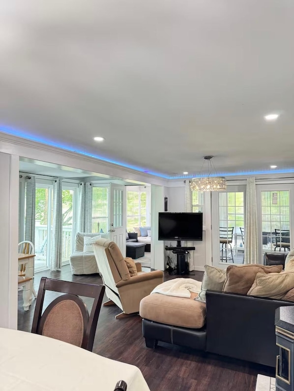 A spacious living room with a large TV, comfortable seating, and large windows.