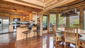 Een ruime keuken met houten keukenkastjes, een centraal eiland en een eetgedeelte met een houten tafel en stoelen.