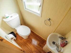Ein kleines Badezimmer mit Toilette, Waschbecken und einem Fenster über der Toilette.