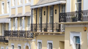 Ein mehrstöckiges Gebäude mit Balkonen, einem Schild mit der Aufschrift 'MARINA COURT' und einem Schild mit 'wine@7' im Fenster.
