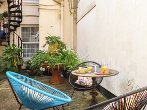 A small patio area with a blue chair, a table with croissants and orange juice, and potted plants. - Boats Galore - Torquay Marina&nbsp; (Torquay)