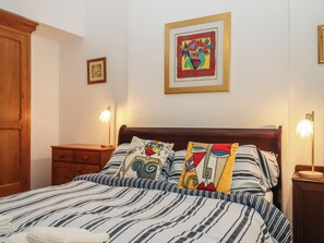 A bedroom with a striped bedspread, a wooden headboard, bedside lamps, a wooden nightstand, and a framed artwork on the wall. - Boats Galore - Torquay Marina&nbsp; (Torquay)