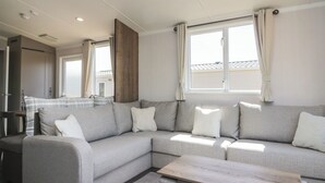 Una sala de estar moderna con un sofá seccional gris, una mesa de centro de madera y vistas a un edificio a través de una ventana.